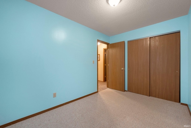 unfurnished bedroom with light colored carpet, a textured ceiling, and a closet