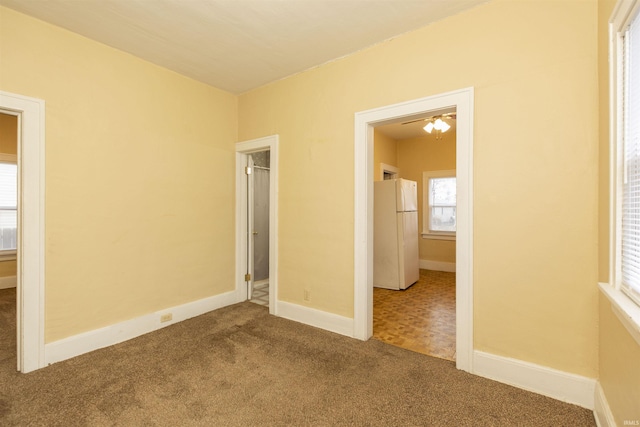 unfurnished bedroom with white refrigerator and carpet floors