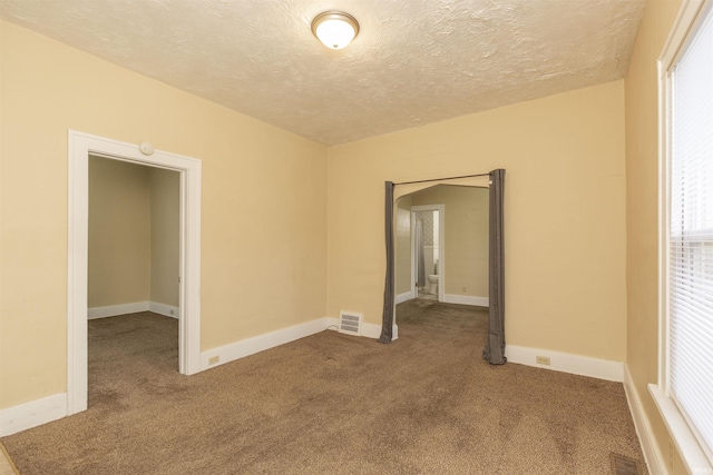 carpeted empty room with a textured ceiling