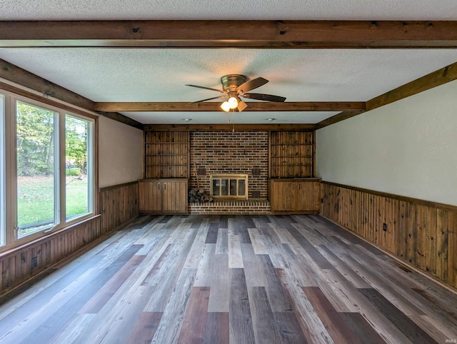 unfurnished living room with beam ceiling, a brick fireplace, and a textured ceiling