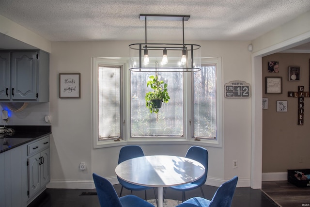 dining room featuring dark wood-type flooring, a wealth of natural light, a textured ceiling, and an inviting chandelier