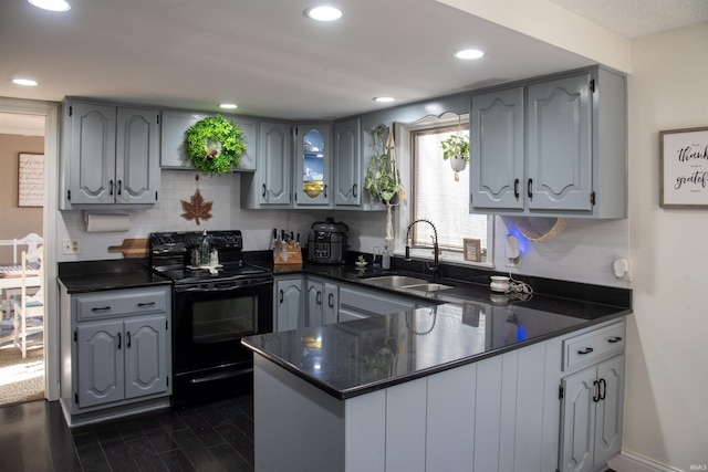 kitchen with sink, backsplash, dark hardwood / wood-style flooring, electric range, and kitchen peninsula