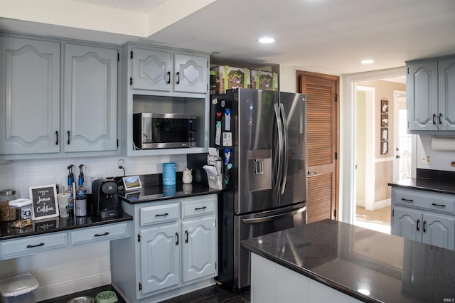 kitchen featuring tasteful backsplash, gray cabinets, stainless steel appliances, and dark stone countertops