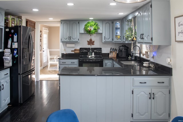 kitchen featuring dark hardwood / wood-style floors, stainless steel fridge with ice dispenser, sink, kitchen peninsula, and black range with electric stovetop