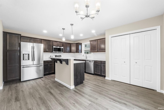 kitchen with sink, a breakfast bar area, a center island, pendant lighting, and stainless steel appliances