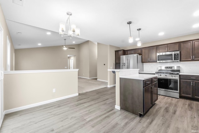 kitchen with dark brown cabinets, appliances with stainless steel finishes, hanging light fixtures, and a kitchen island