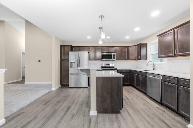 kitchen with sink, hanging light fixtures, a kitchen island, stainless steel appliances, and backsplash