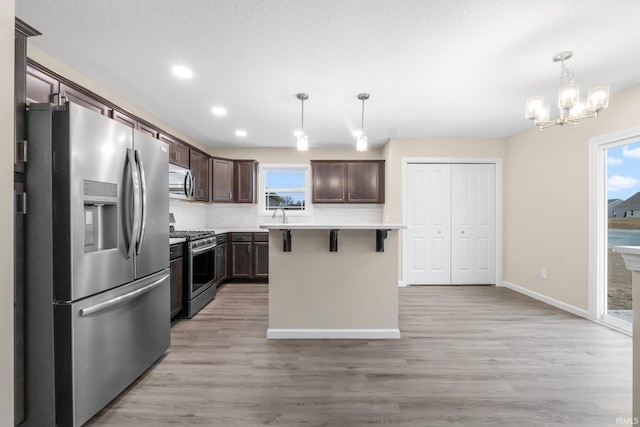 kitchen featuring hanging light fixtures, a breakfast bar area, stainless steel appliances, and a kitchen island