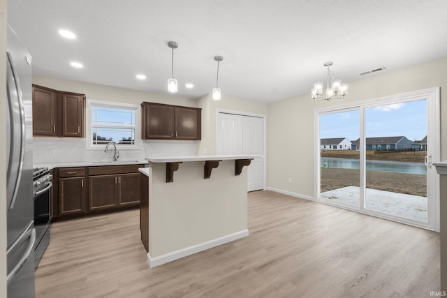 kitchen featuring a water view, a breakfast bar, pendant lighting, and sink