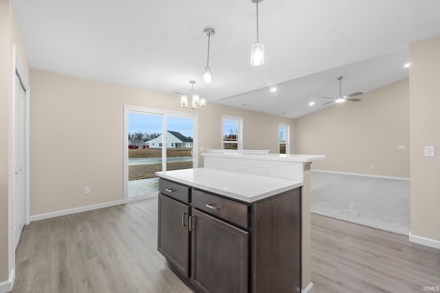 kitchen with light hardwood / wood-style flooring, decorative light fixtures, dark brown cabinets, and a center island