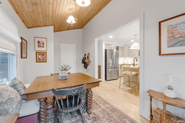 dining area with sink, vaulted ceiling, light hardwood / wood-style flooring, and wooden ceiling