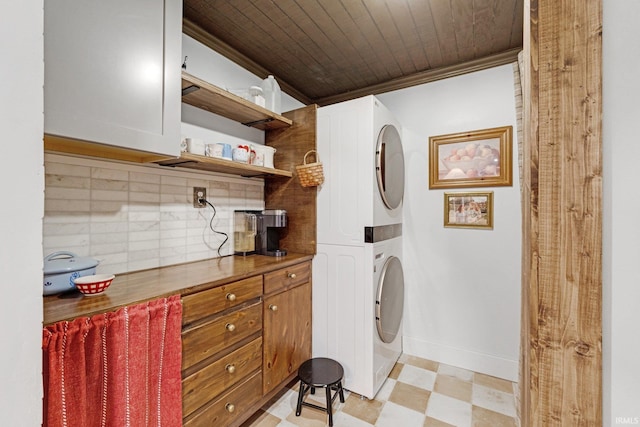 laundry room featuring crown molding, wooden ceiling, and stacked washing maching and dryer