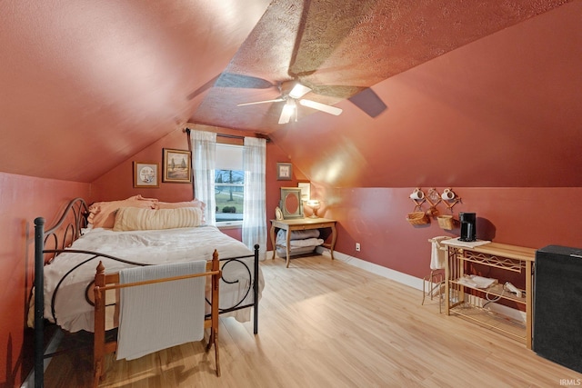 bedroom featuring ceiling fan, lofted ceiling, hardwood / wood-style floors, and a textured ceiling