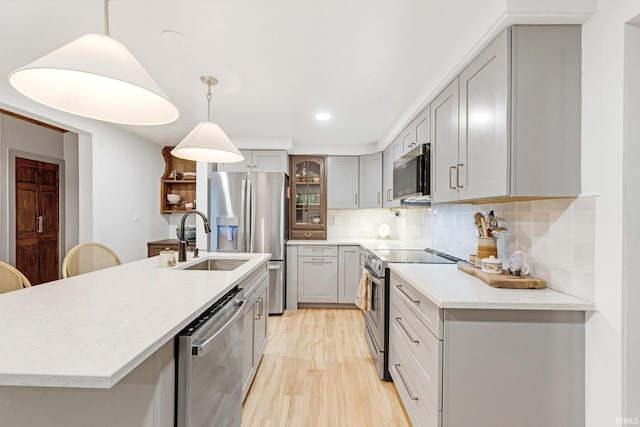 kitchen with stainless steel appliances, sink, gray cabinets, and decorative light fixtures