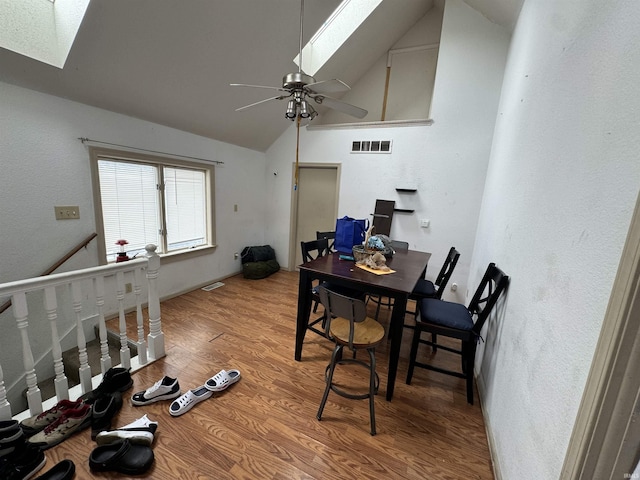 dining room featuring ceiling fan, wood-type flooring, a skylight, and high vaulted ceiling