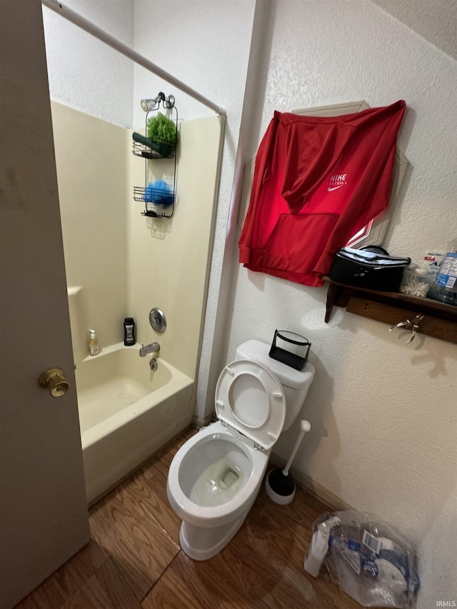 bathroom featuring hardwood / wood-style flooring, bathtub / shower combination, and toilet