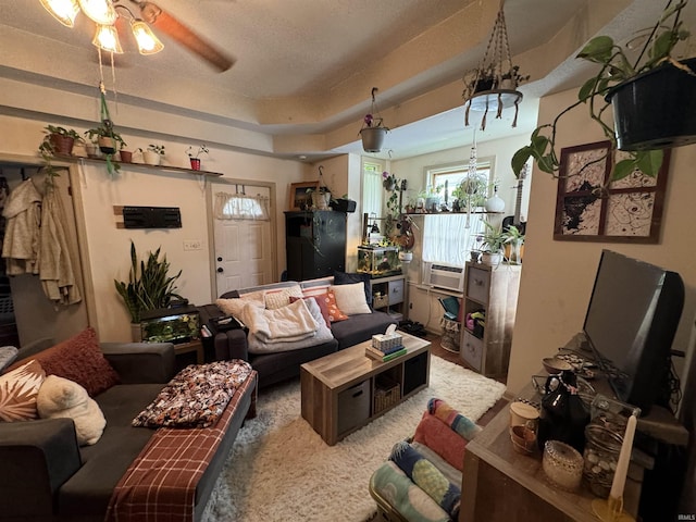 living room featuring ceiling fan, a tray ceiling, and a textured ceiling