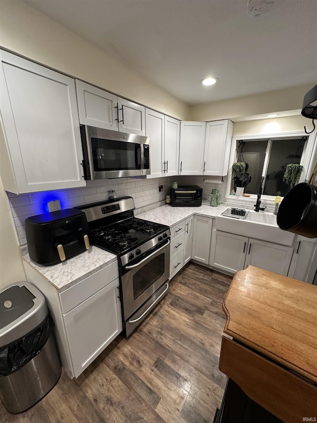 kitchen with sink, stainless steel appliances, dark hardwood / wood-style floors, tasteful backsplash, and white cabinets