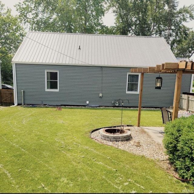 rear view of house featuring a fire pit and a lawn