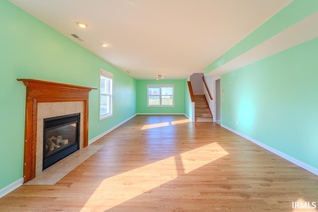 unfurnished living room with a tiled fireplace and light hardwood / wood-style flooring