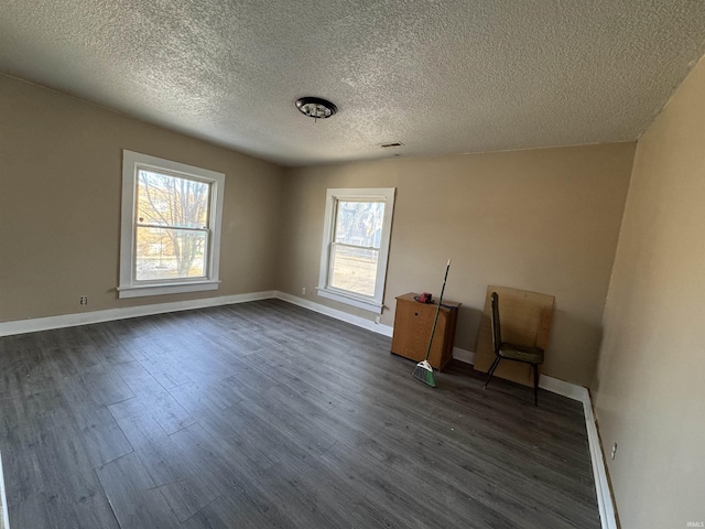 unfurnished room featuring dark wood-type flooring and a textured ceiling