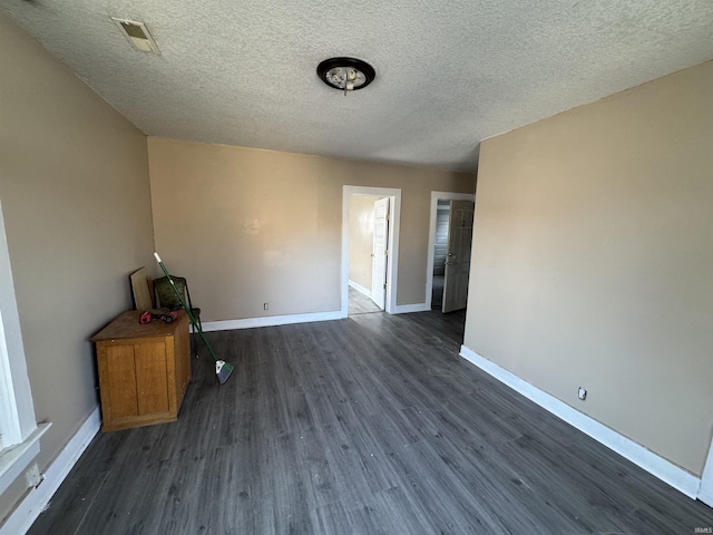 empty room featuring dark hardwood / wood-style flooring and a textured ceiling