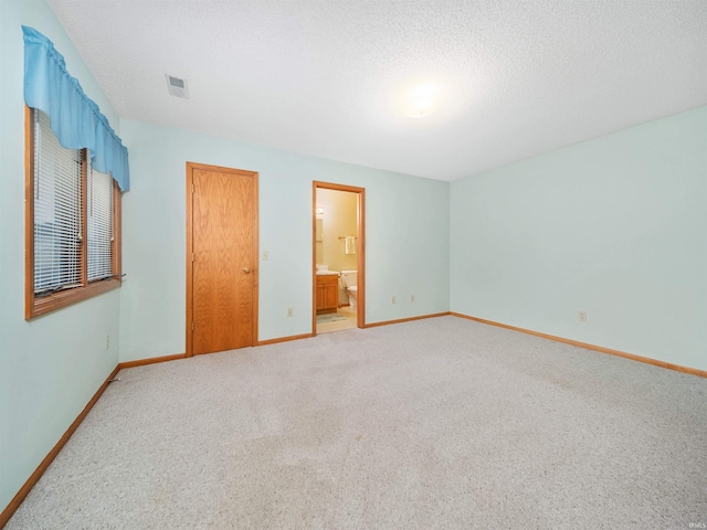 unfurnished bedroom featuring connected bathroom, carpet flooring, and a textured ceiling