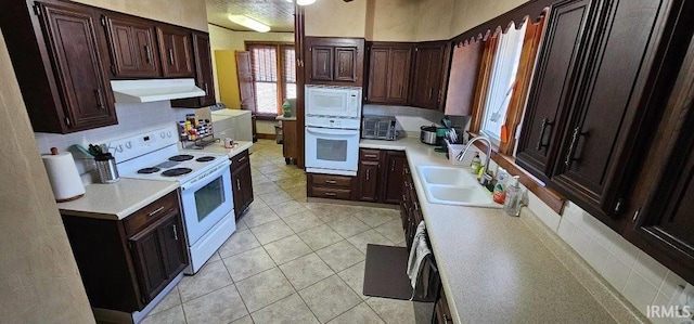 kitchen with sink, tasteful backsplash, light tile patterned floors, white appliances, and washer / clothes dryer