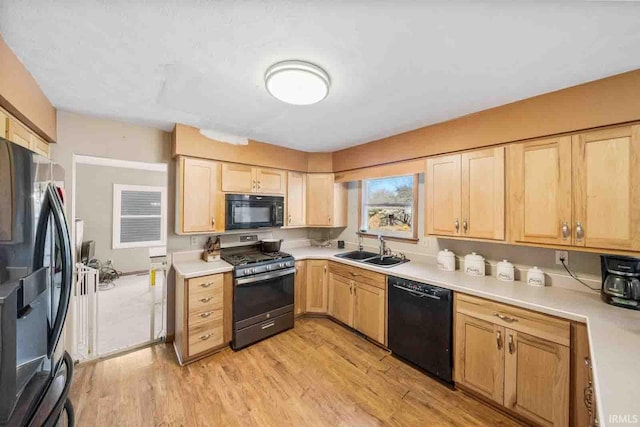 kitchen with sink, light hardwood / wood-style flooring, light brown cabinetry, and black appliances