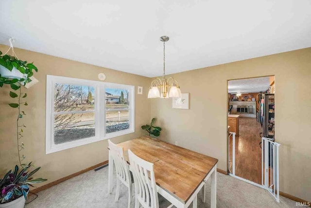 carpeted dining room with a notable chandelier