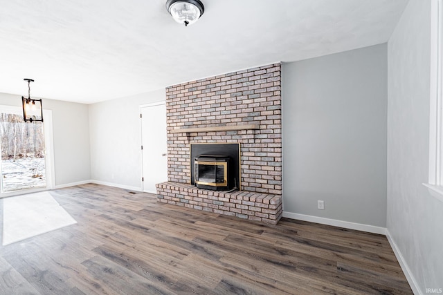 unfurnished living room featuring hardwood / wood-style flooring and a brick fireplace