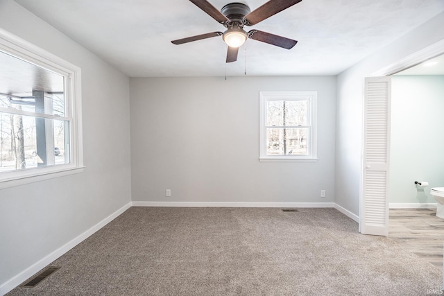 unfurnished bedroom featuring multiple windows, light colored carpet, a closet, and ceiling fan