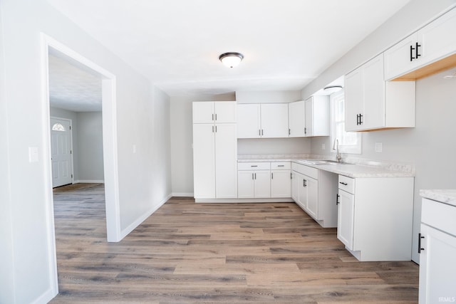 kitchen featuring sink, wood-type flooring, and white cabinets