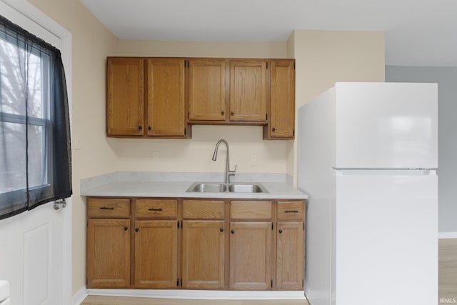 kitchen with white refrigerator, sink, and light hardwood / wood-style flooring