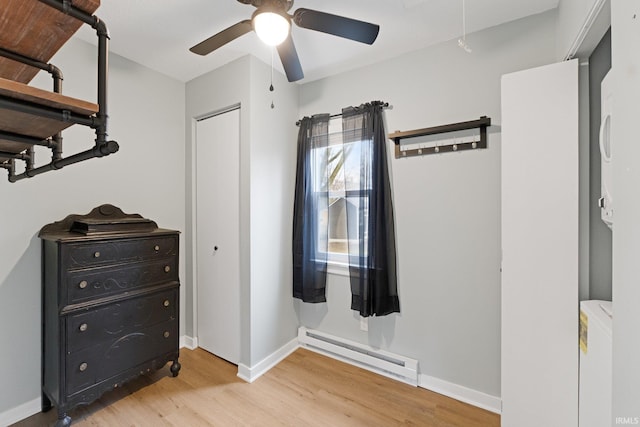 bedroom featuring a baseboard heating unit, ceiling fan, and light wood-type flooring