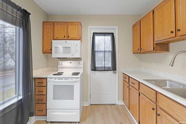 kitchen with sink, white appliances, and light hardwood / wood-style flooring