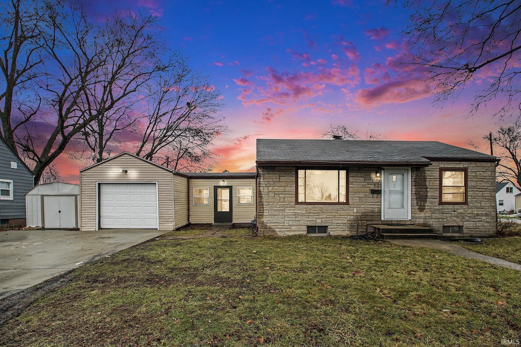 view of front of house featuring a storage unit, a yard, and a garage