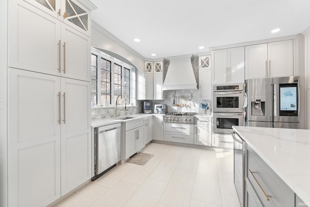 kitchen featuring sink, white cabinetry, stainless steel appliances, light stone counters, and custom exhaust hood