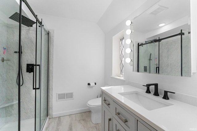 bathroom featuring vanity, a shower with shower door, hardwood / wood-style floors, and toilet