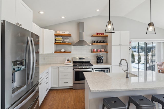 kitchen featuring stainless steel appliances, a breakfast bar, decorative light fixtures, and wall chimney exhaust hood