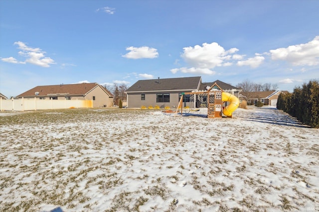 snow covered rear of property featuring a playground