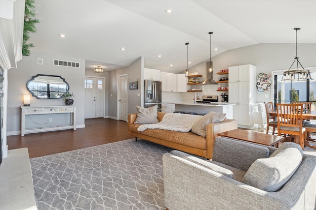 living room featuring sink, a chandelier, vaulted ceiling, plenty of natural light, and dark hardwood / wood-style flooring