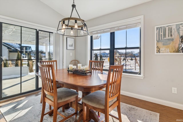 dining space with lofted ceiling, hardwood / wood-style floors, and a notable chandelier