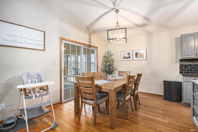 dining room featuring vaulted ceiling, an inviting chandelier, and light hardwood / wood-style flooring