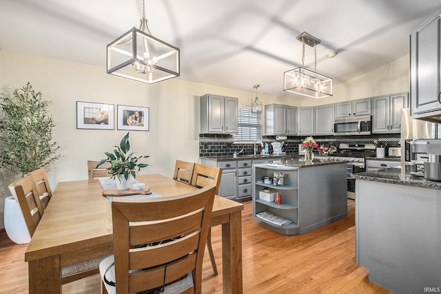 kitchen with pendant lighting, gray cabinetry, stainless steel appliances, and a kitchen island