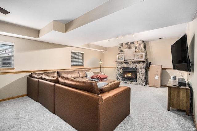 carpeted living room with a stone fireplace