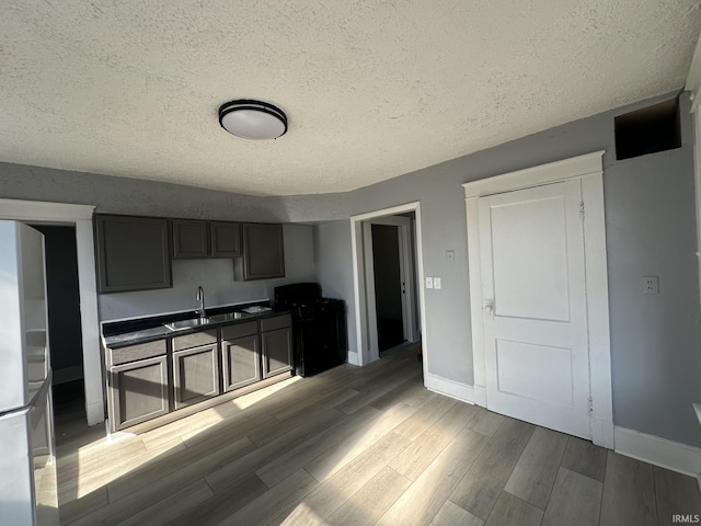 kitchen featuring sink, wood-type flooring, and a textured ceiling