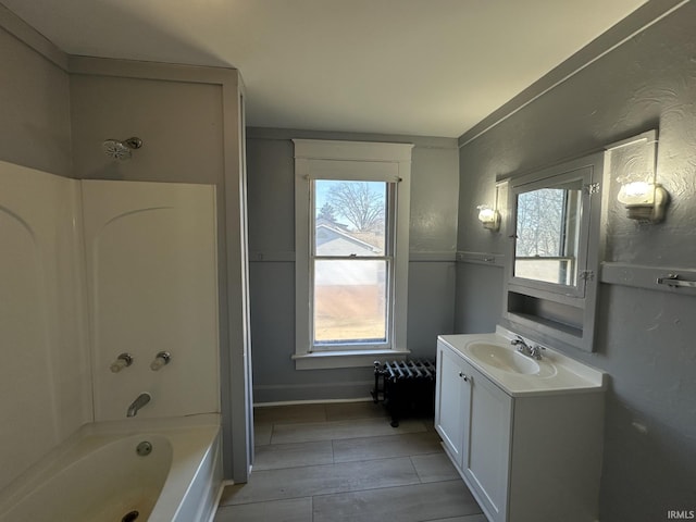 bathroom with a healthy amount of sunlight, washtub / shower combination, and vanity