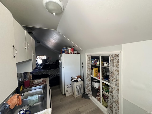 interior space featuring white refrigerator, vaulted ceiling, and white cabinets