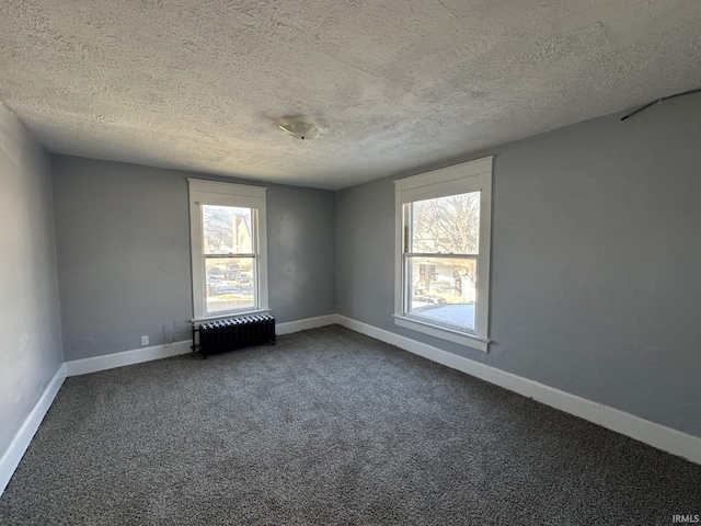 empty room featuring carpet, radiator, and a textured ceiling